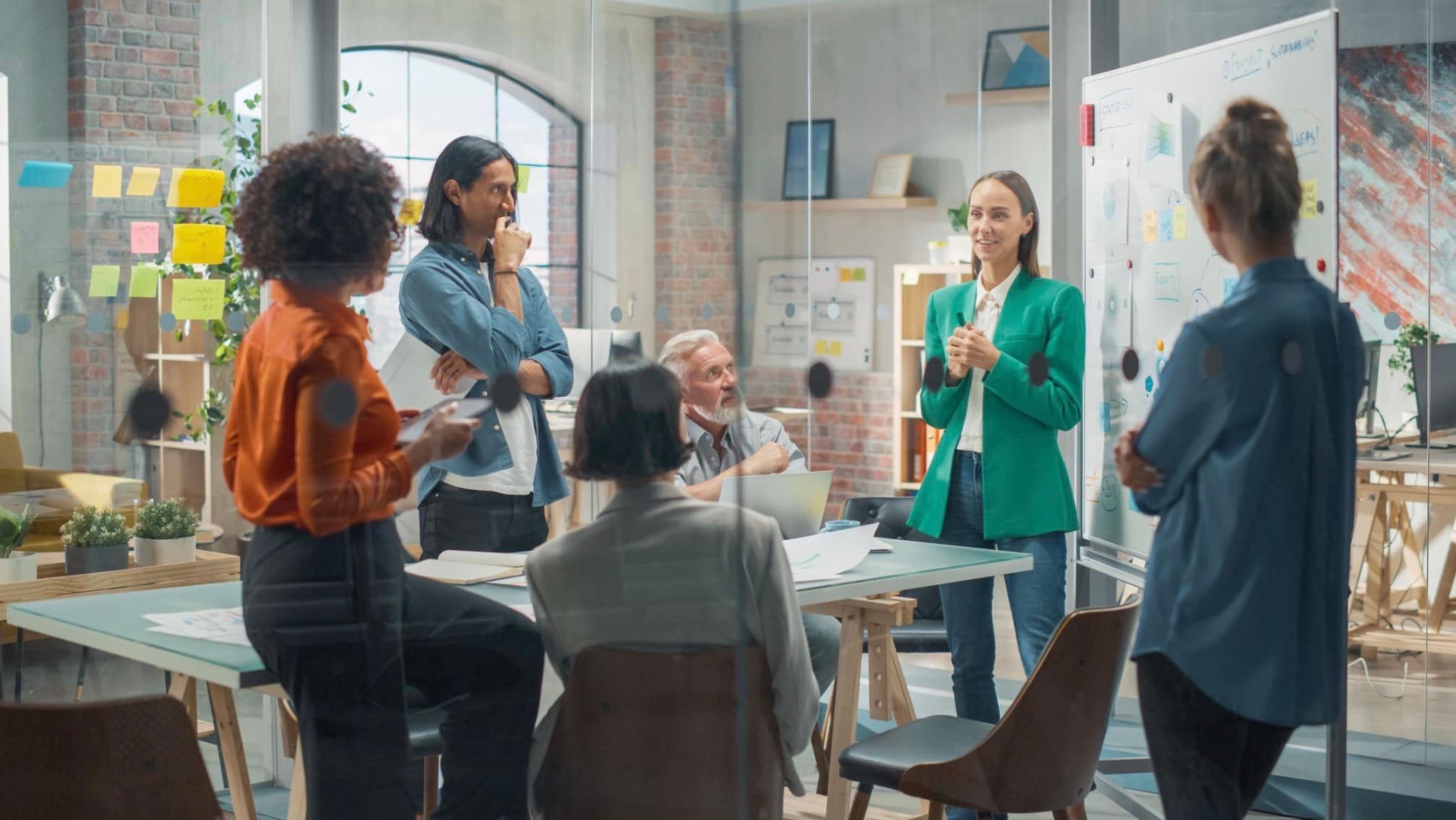 A team collaborating in a workplace, gathered around a whiteboard
